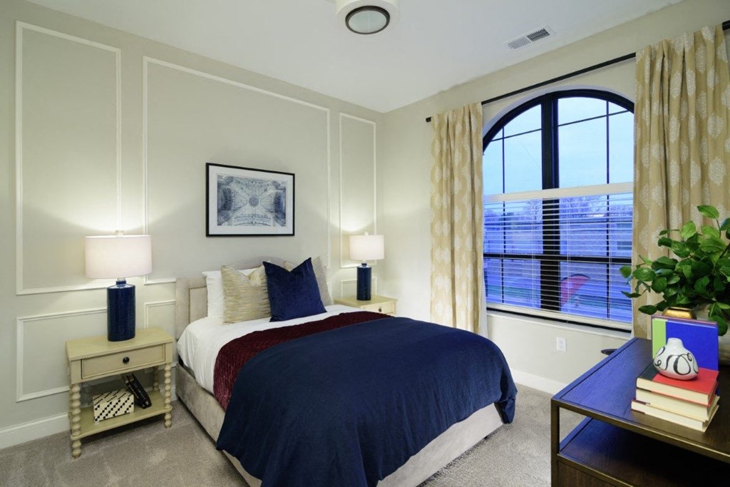 a bedroom with a large window and a bed with a blue comforter  Fairfax, Grandview