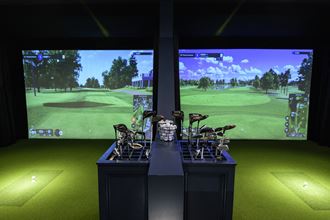 a display of golf equipment in front of a large screen of a golf course