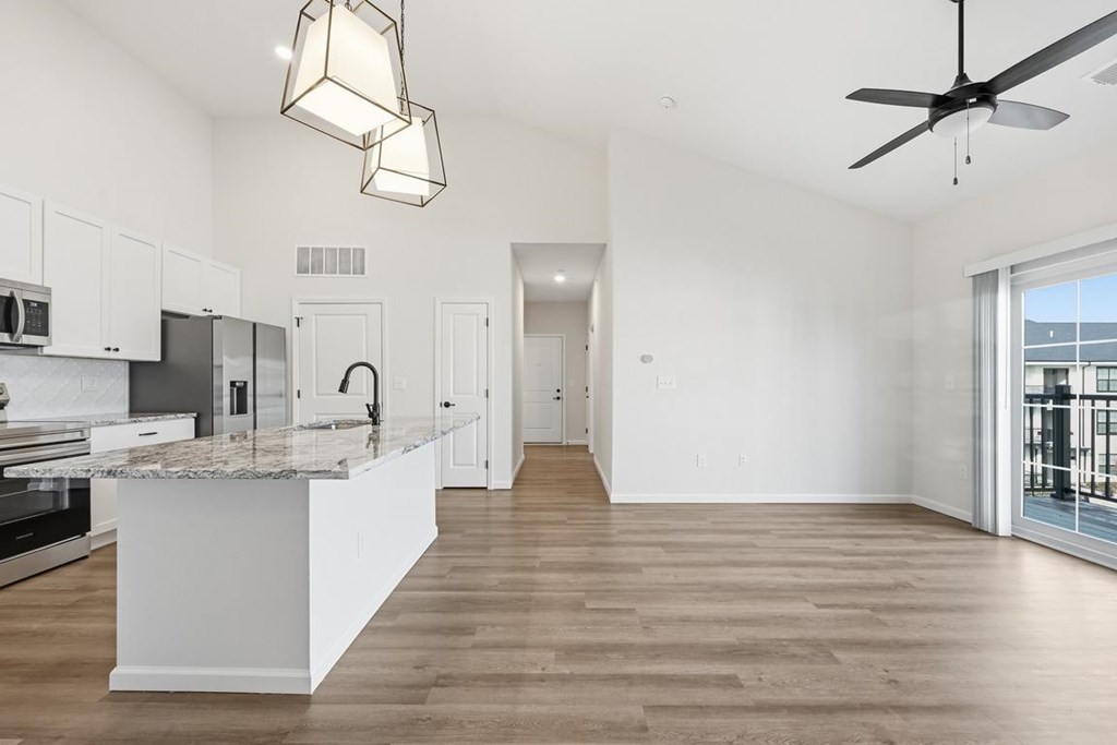 A modern kitchen with a marble countertop and a ceiling fan.