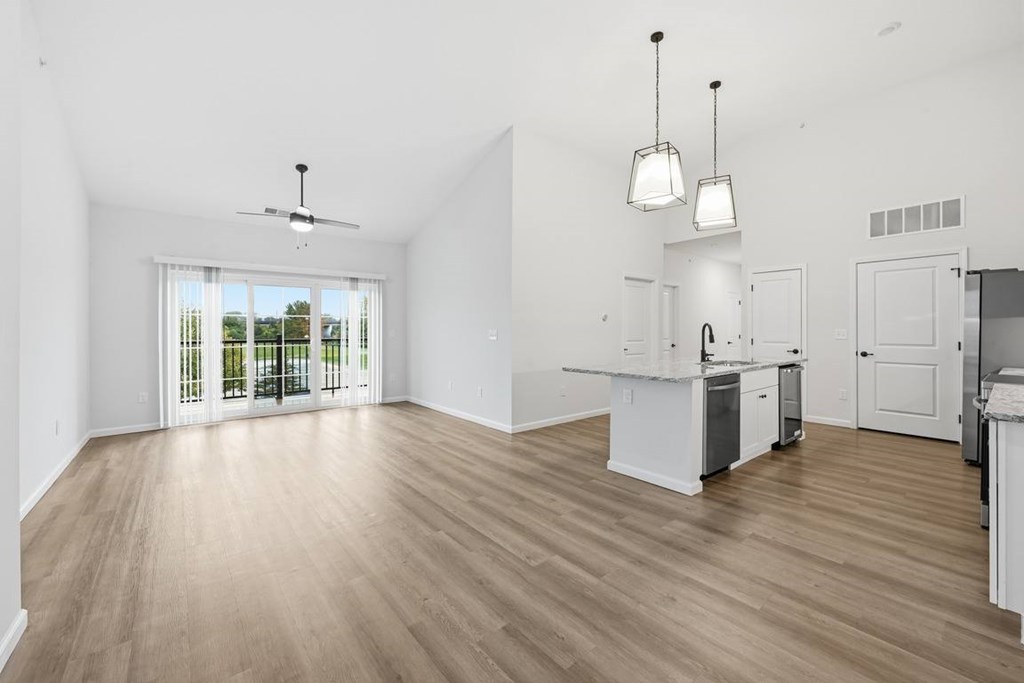 A spacious kitchen with white cabinets and a wooden floor.