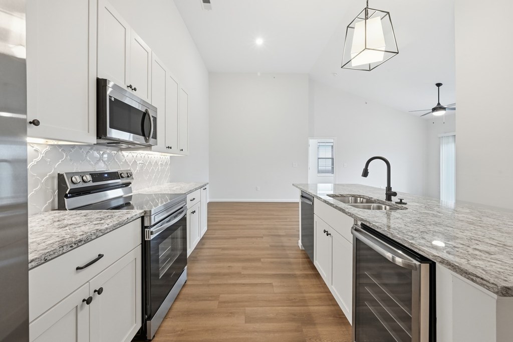 A modern kitchen with a marble countertop and stainless steel appliances.
