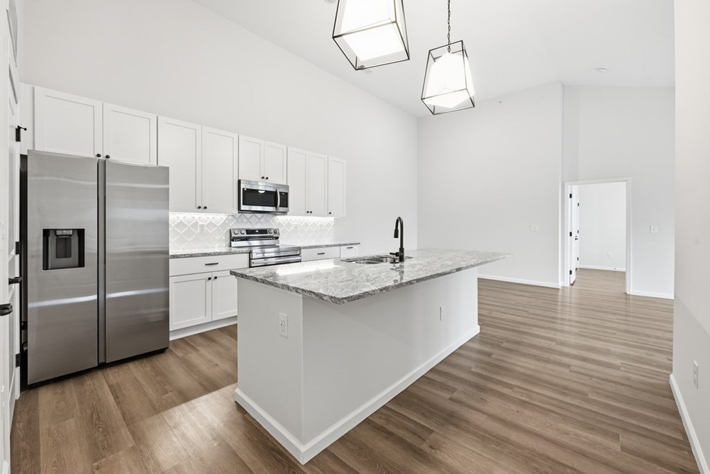A kitchen with a stainless steel refrigerator, microwave, and oven.