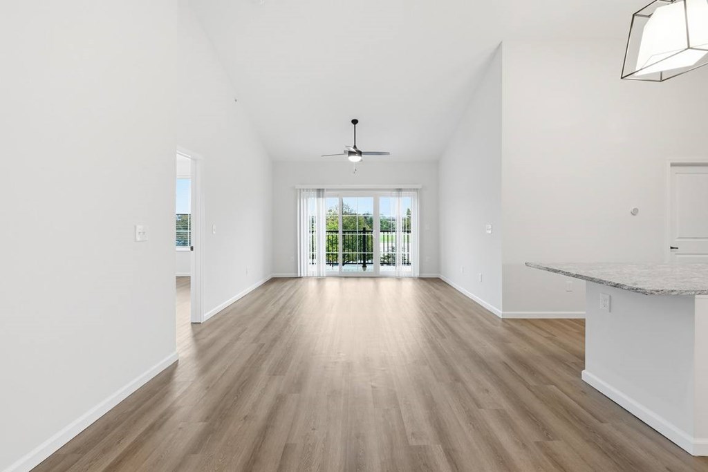 A spacious room with wooden flooring and a ceiling fan.