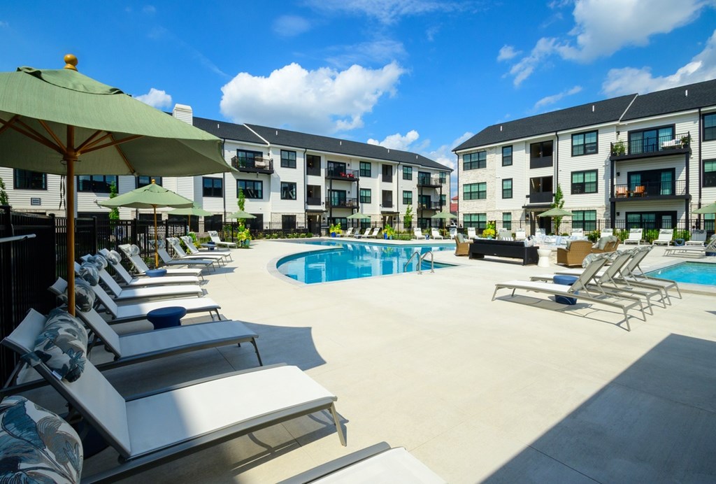 A sunny day at the poolside with chairs and umbrellas.