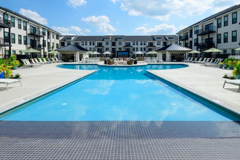 A large swimming pool in the middle of a resort surrounded by buildings.