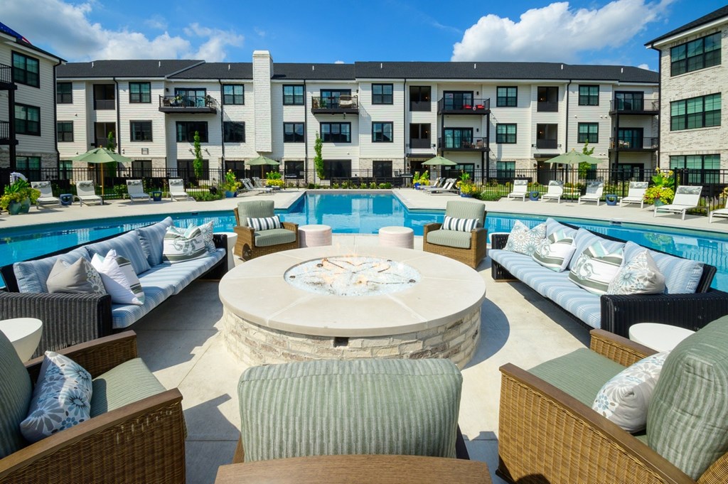 A large outdoor pool area with a fountain in the middle of a patio.