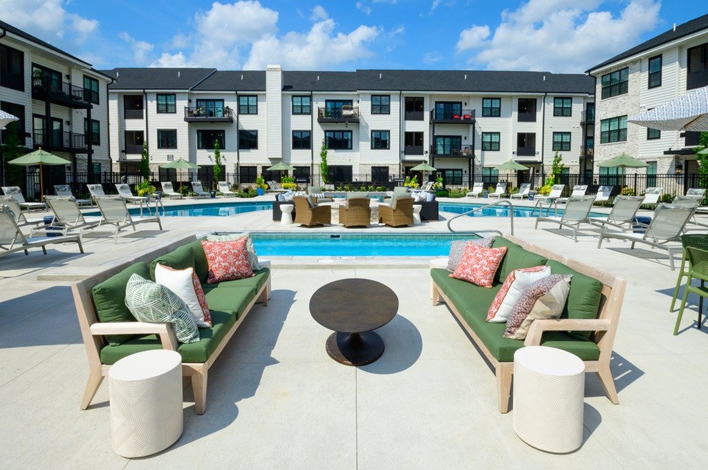A pool surrounded by lounge chairs and tables.