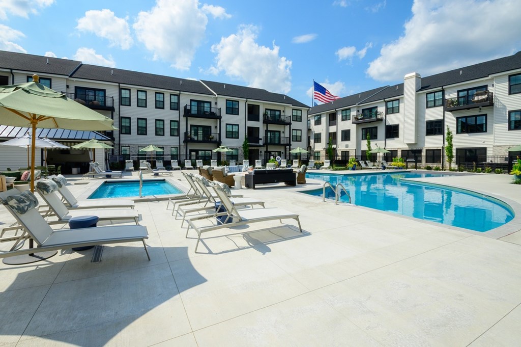 A pool area with sun loungers and a building in the background.