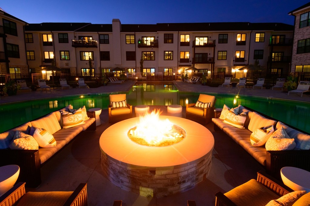 A fire pit in the middle of a patio surrounded by couches.
