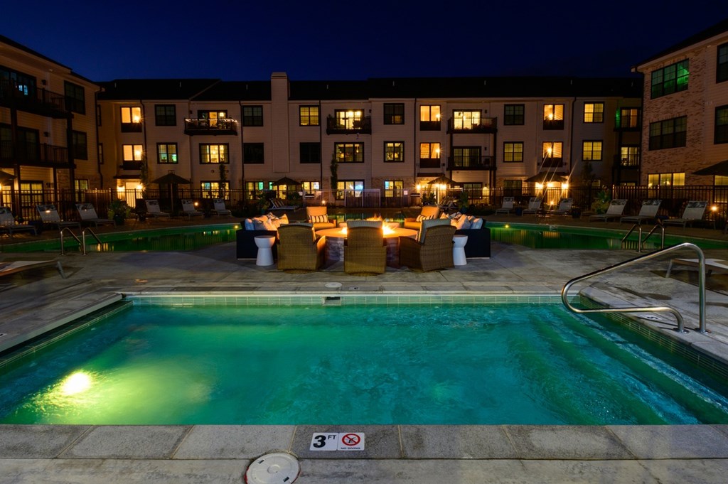 A swimming pool at night with lights on.