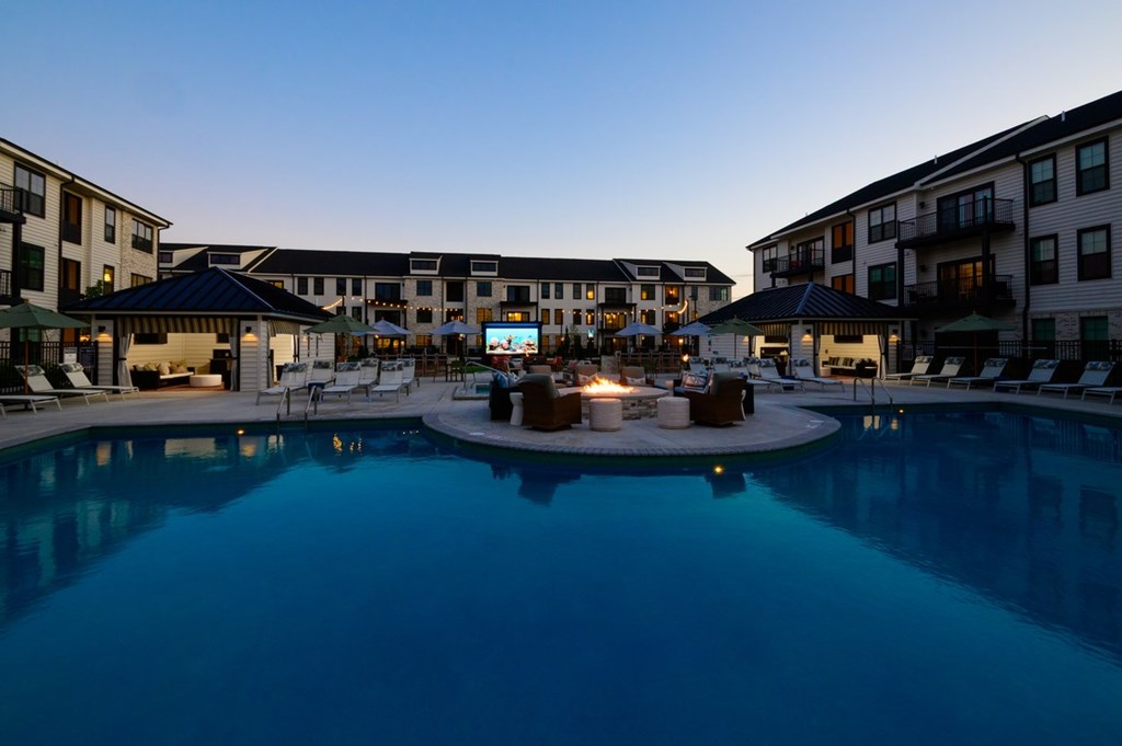 A swimming pool surrounded by apartment buildings at dusk.