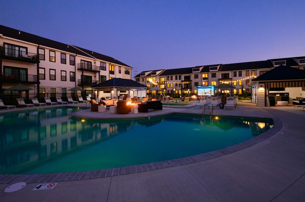A swimming pool surrounded by buildings at dusk.