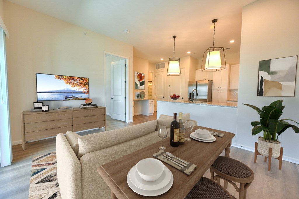 A modern dining room with a wooden table set for two.