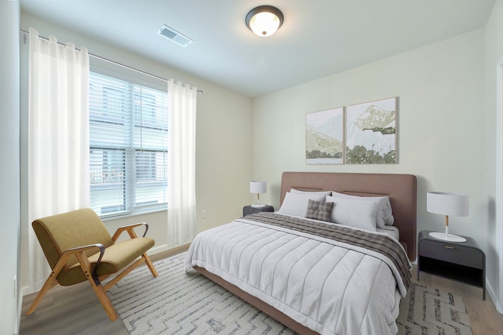A bedroom with a bed, chair, and two pictures on the wall.