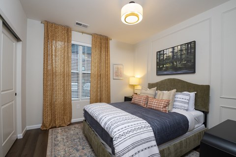 A bedroom with a large bed and a painting on the wall.