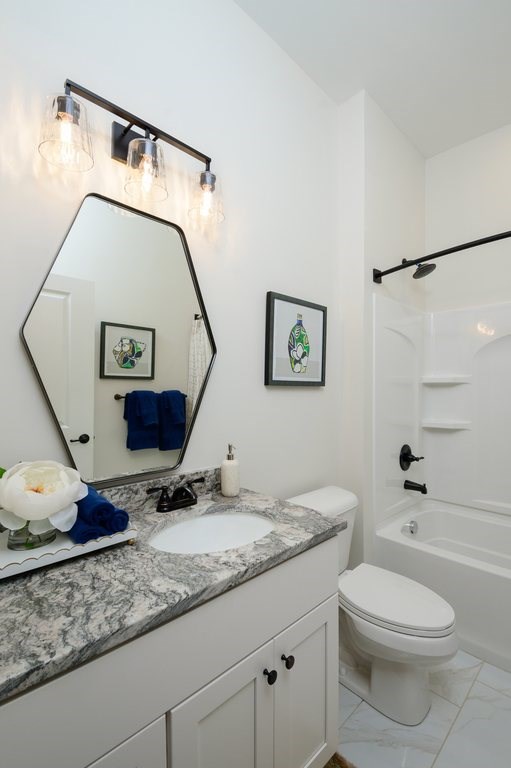 A bathroom with a white toilet and a marble counter top.