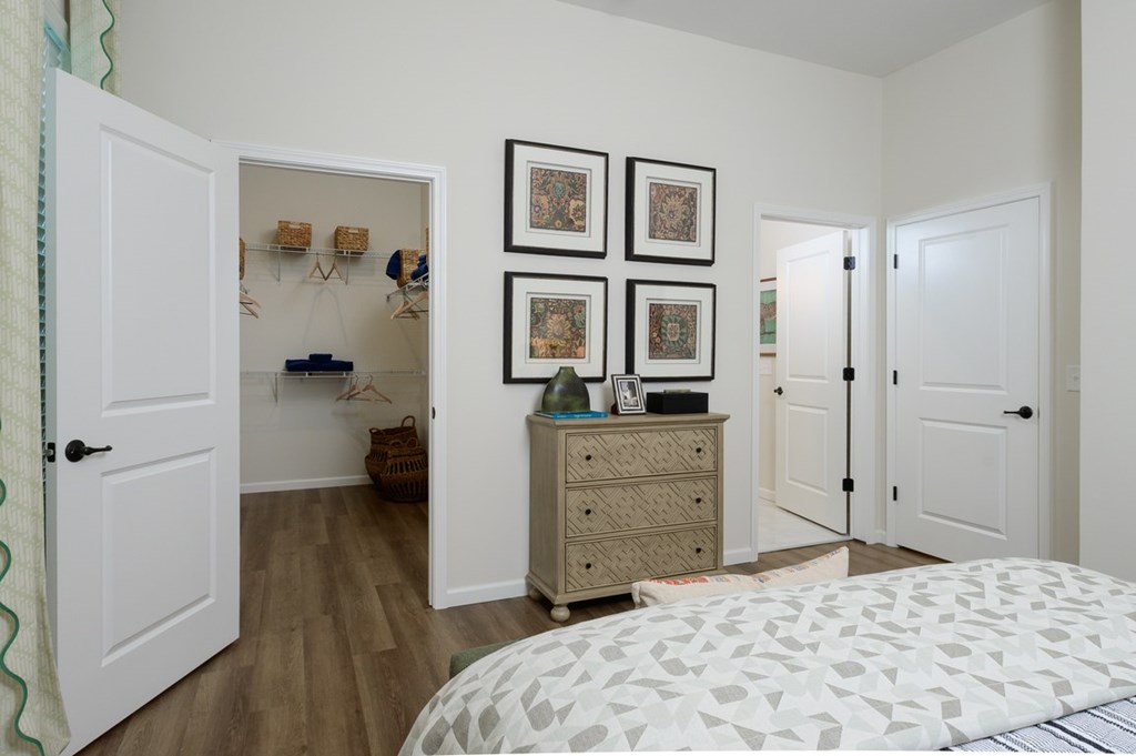 A bedroom with a white bed and a dresser with three drawers.