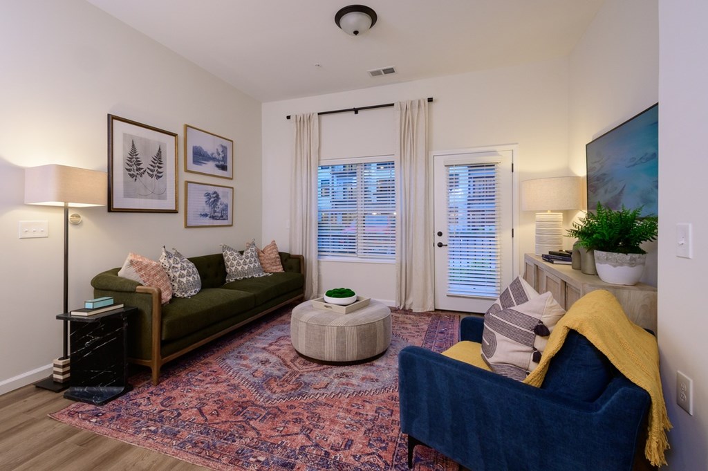A living room with a blue couch and a rug.