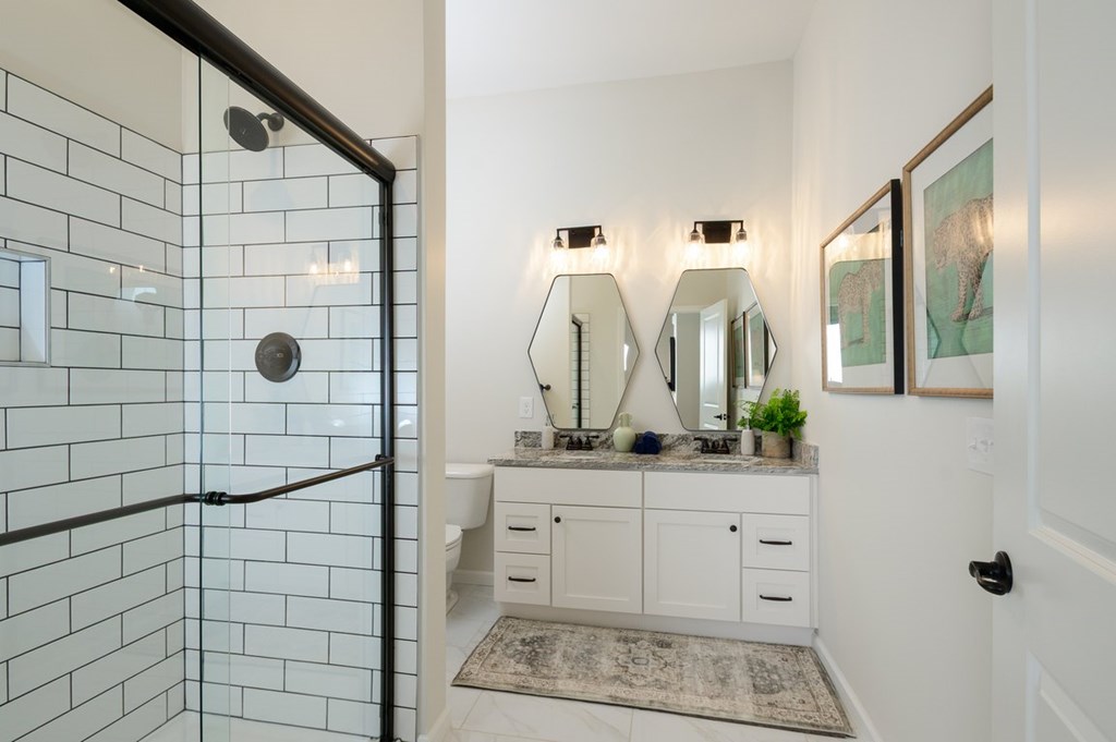 A bathroom with a glass shower door and a vanity with a mirror above it.