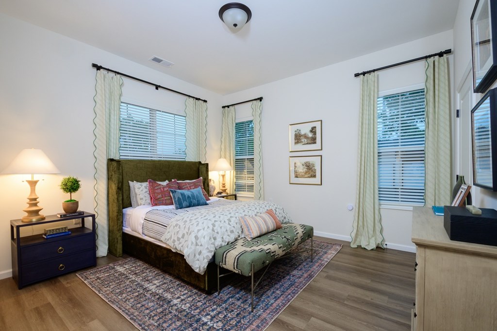 A bedroom with a large bed and a nightstand with a lamp.