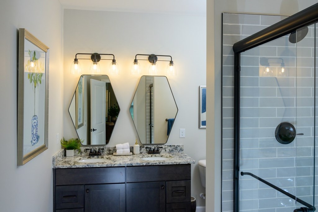 A bathroom with a marble countertop and a large mirror above it.