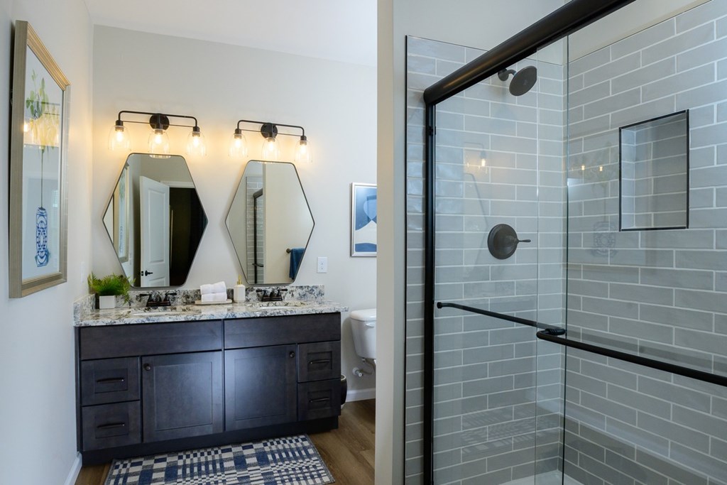 A bathroom with a black vanity and a glass shower.