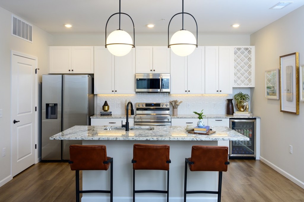 A kitchen with a marble countertop and white cabinets.
