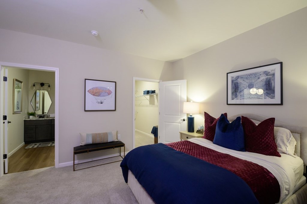 A bedroom with a bed, nightstands, and a painting on the wall.