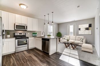 a kitchen and living room with white cabinets and stainless steel appliances at Kendall Park, Columbus, OH, 43220