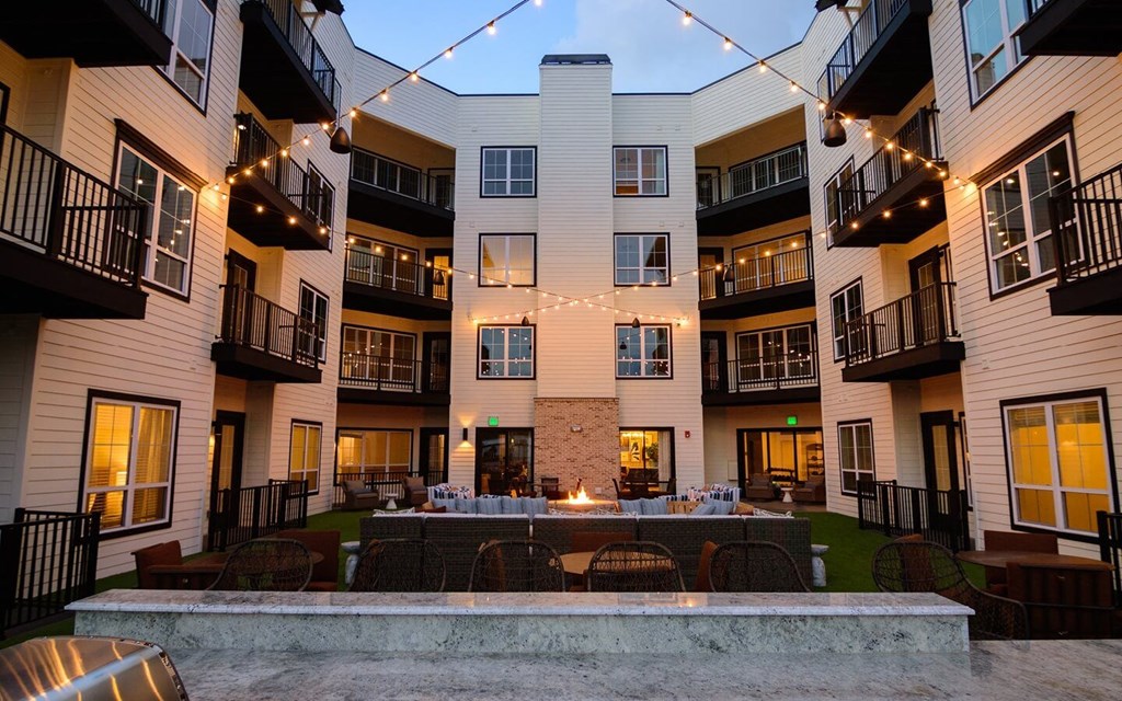 an outdoor patio with a firepit and string lights at the flats at big tex apartments in at Essex, Ohio, 43212
