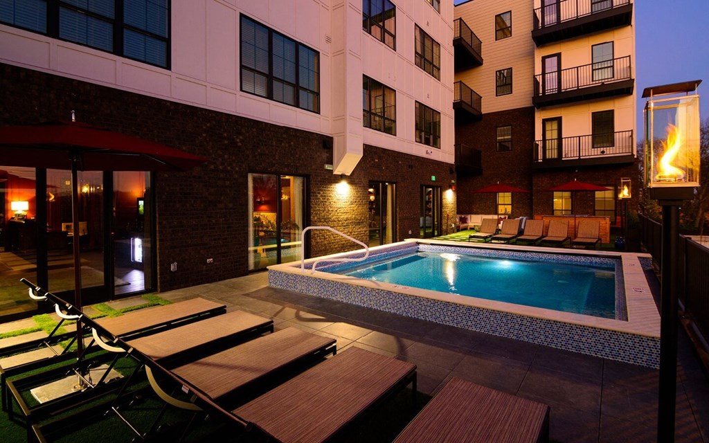 a pool with lounge chairs and umbrellas in front of an apartment building at Fairfax, Grandview, 43212