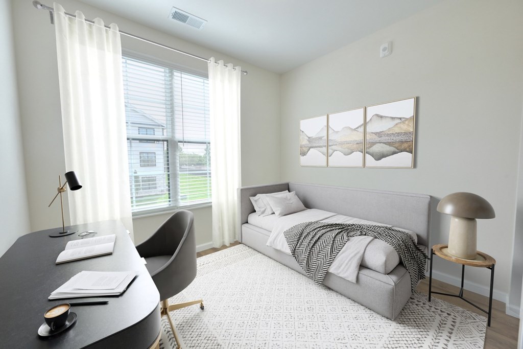 A bedroom with a bed, chair, and desk.