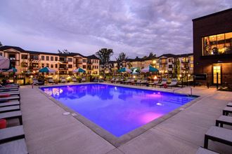 a swimming pool at night in front of an apartment building