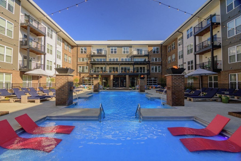 a large swimming pool with red chairs in front of an apartment buildingat Taylor House Apartments, Columbus, Ohio