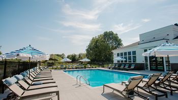 a swimming pool with chaise lounge chairs and umbrellas at Elan Park, Columbus, OH 43231