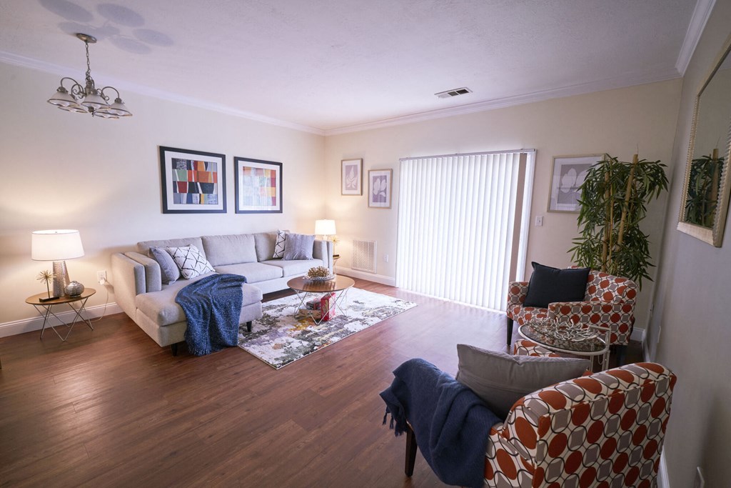 A living room with a grey couch, a chair with a red and white pattern, and a ceiling fan.