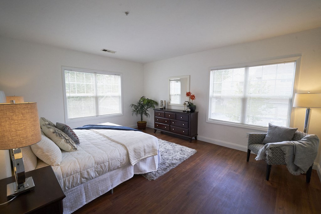 A bedroom with a large bed, a chair, and a dresser.