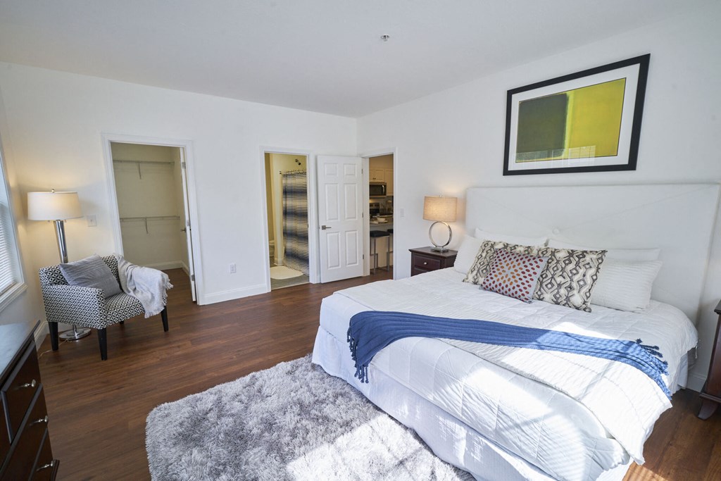 A bedroom with a large bed and a chair.