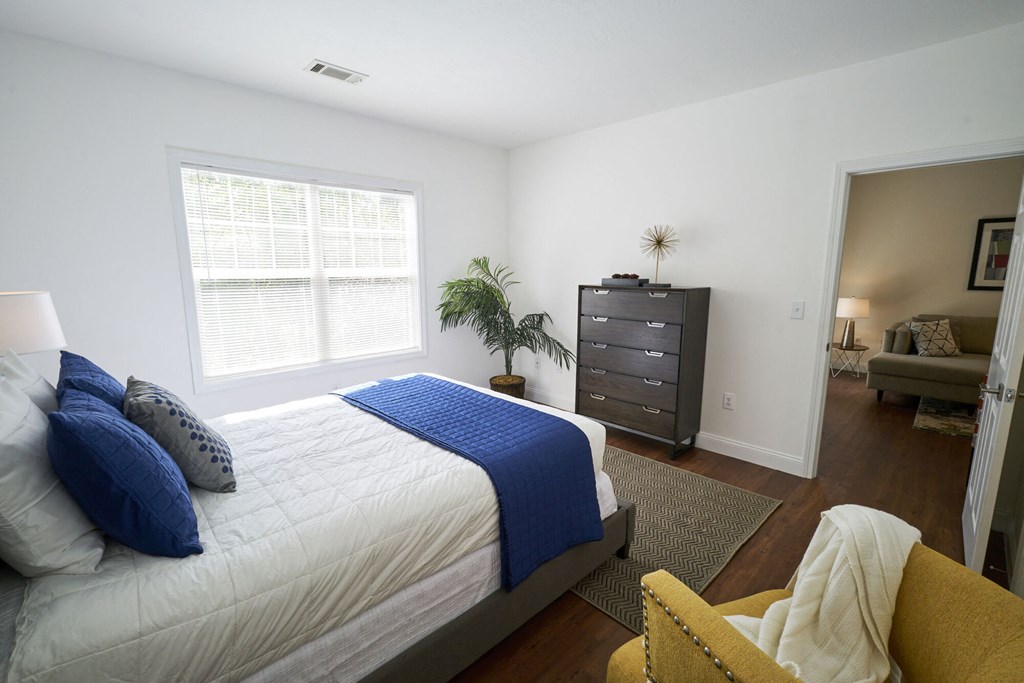 A bedroom with a bed, dresser, and chair.