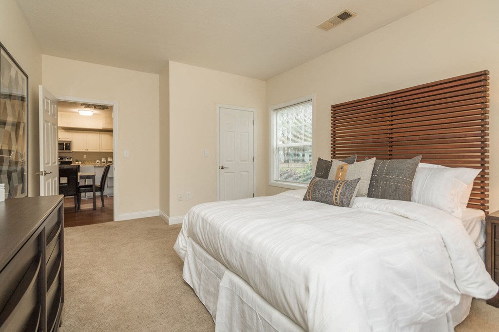 A bedroom with a large bed and a window with blinds.