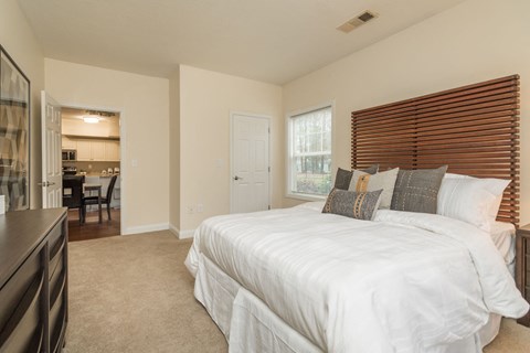 A bedroom with a large bed and a window with blinds.