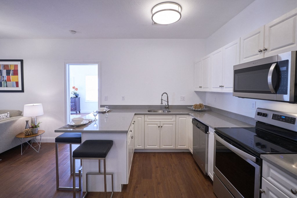 A kitchen with white cabinets and black countertops.