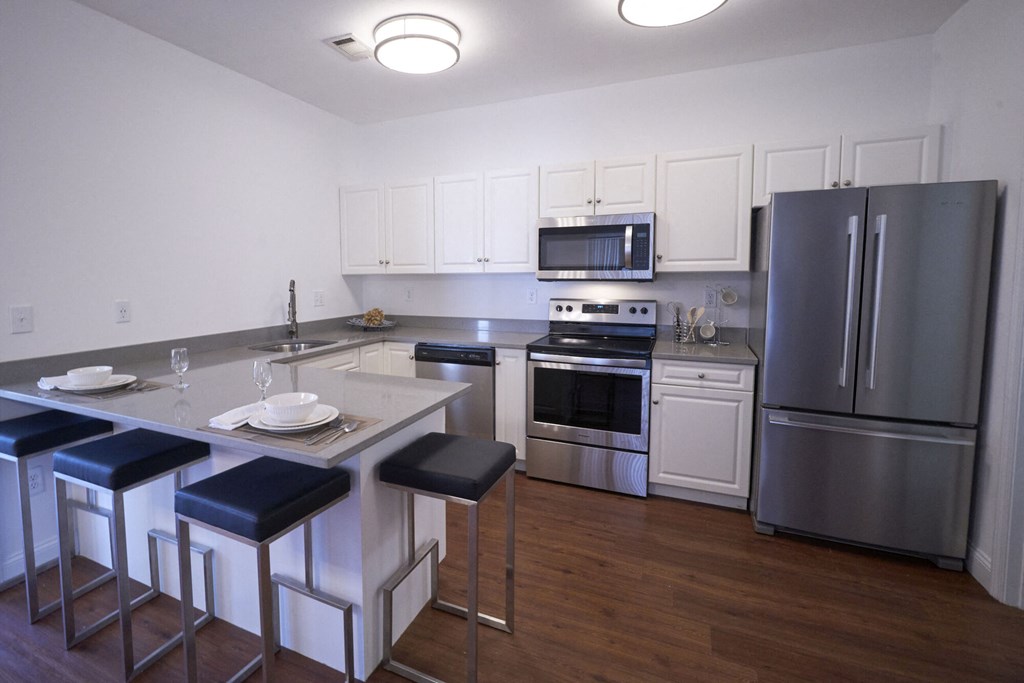 A kitchen with a white counter top and stainless steel appliances.