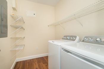 A laundry room with a washer and dryer and a shelving unit.