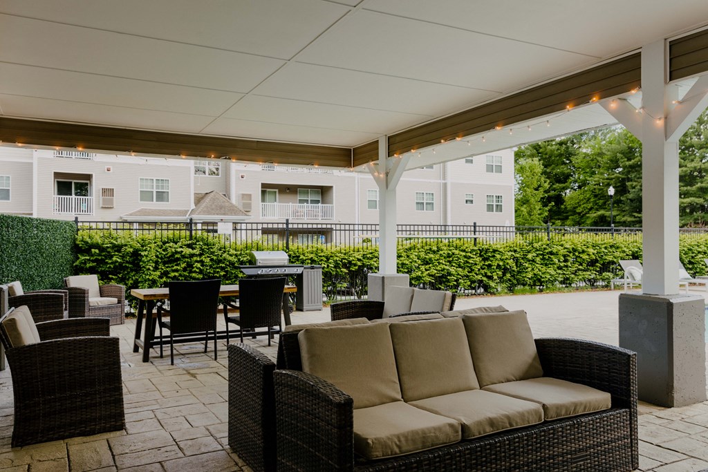 A patio with a sofa, chairs, and a table under a white canopy.