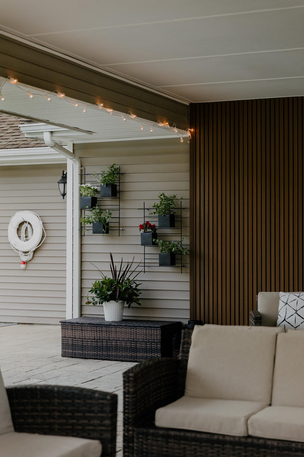 A patio with a wicker couch, chair, and a wall-mounted planter.