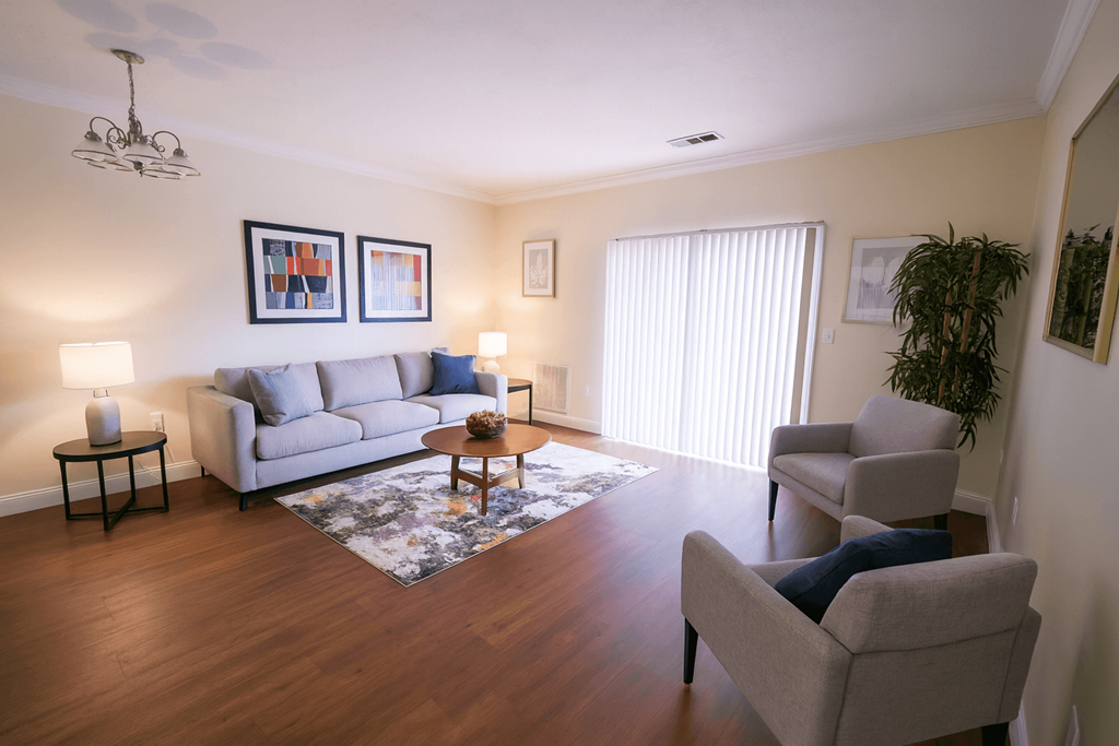A living room with a grey couch, a grey armchair, a coffee table, and a rug.