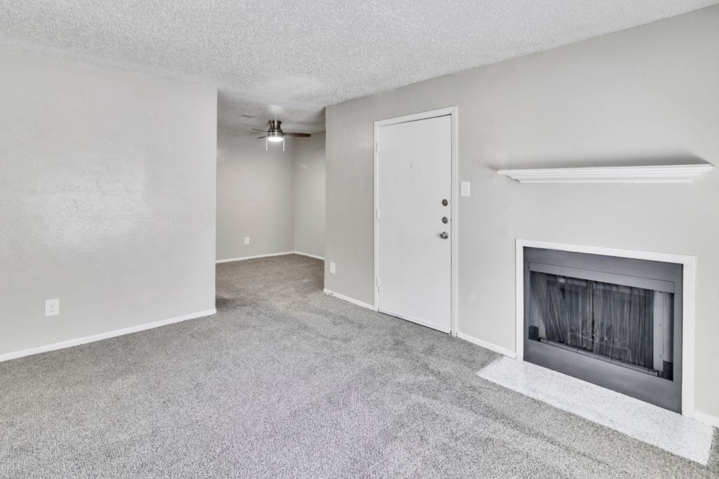 an empty living room with a fireplace and white walls