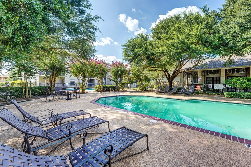 a swimming pool with benches and trees around it