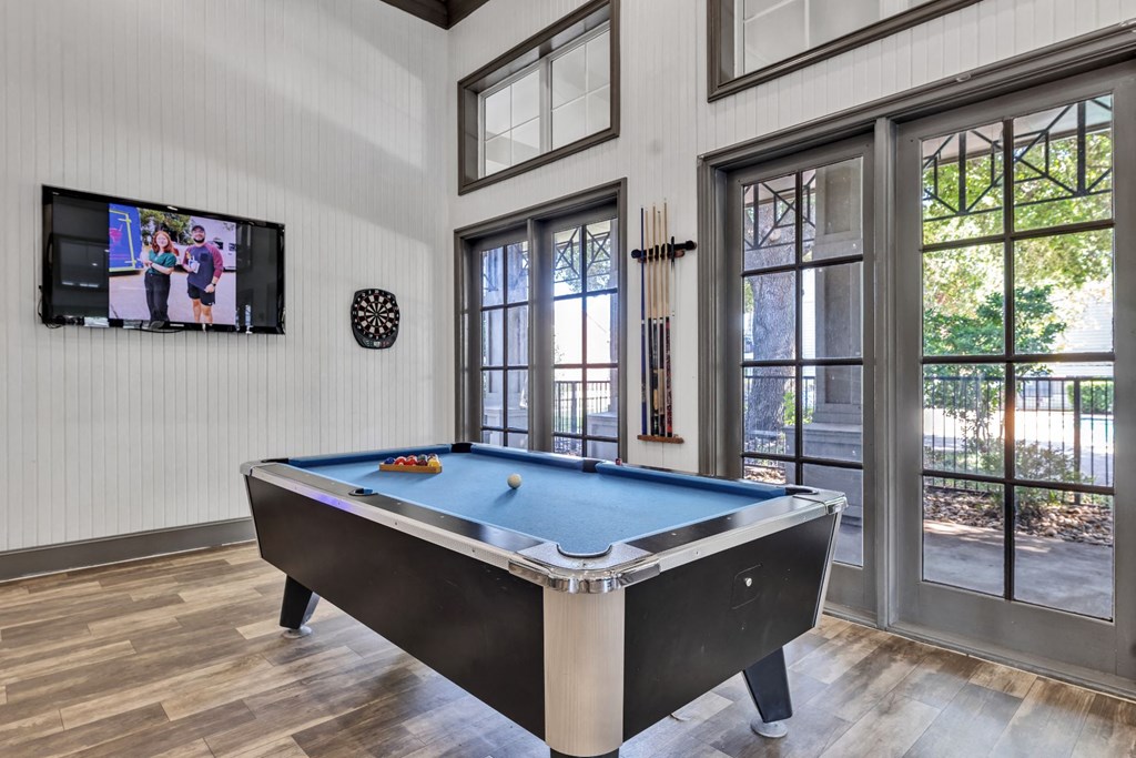 a pool table and a tv in a room with windows